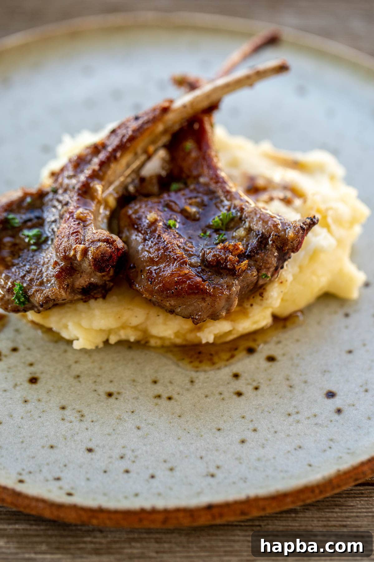 A plate featuring perfectly cooked lamb chops served alongside a generous portion of creamy mashed potatoes.