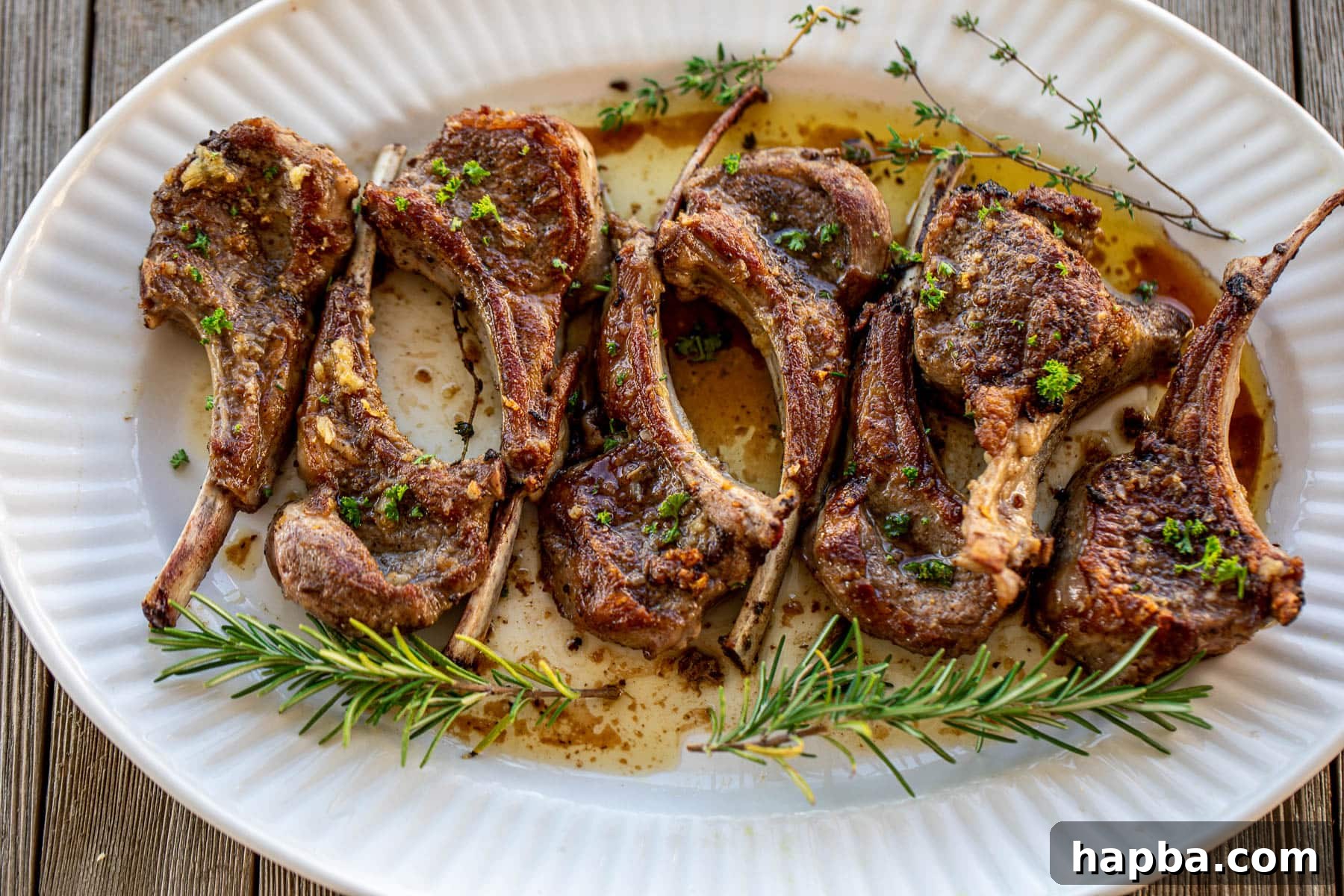 Pan seared lamb chops garnished with fresh parsley on a white platter, ready to be served.
