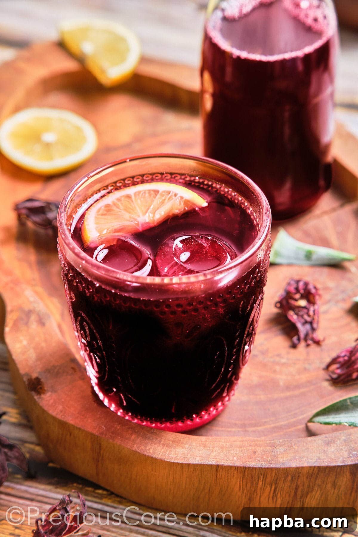 Folere Cameroonian Hibiscus Drink 2 A glass of vibrant red Folere drink, garnished with a slice of lemon, sparkling with ice cubes.