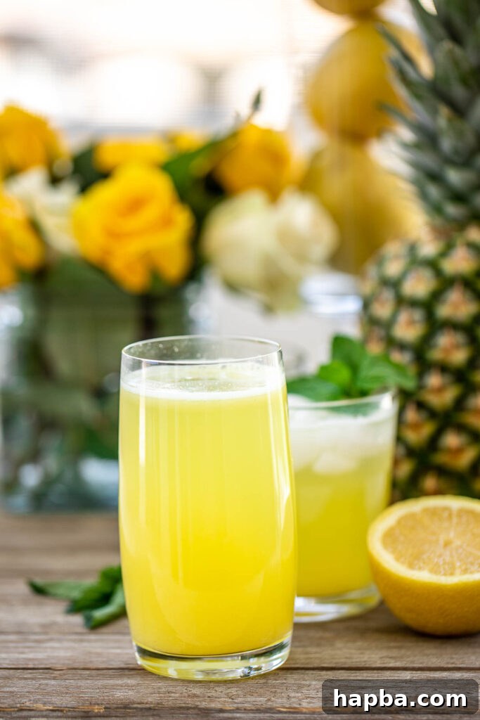 Tropical Zest Lemonade 2 Tall Glass of Pineapple Lemonade with fresh pineapple and lemon slices