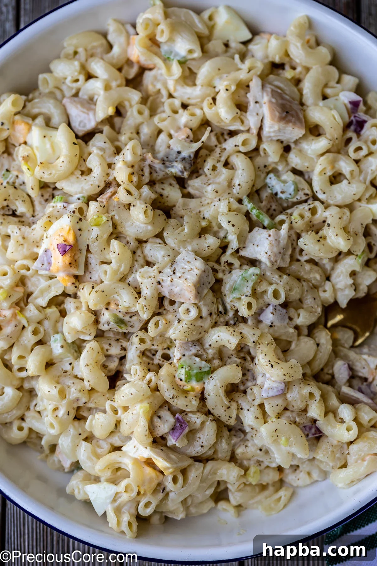 Creamy Chicken Macaroni Delight 11 Close-up of creamy macaroni salad with chicken in a white bowl, garnished with parsley.