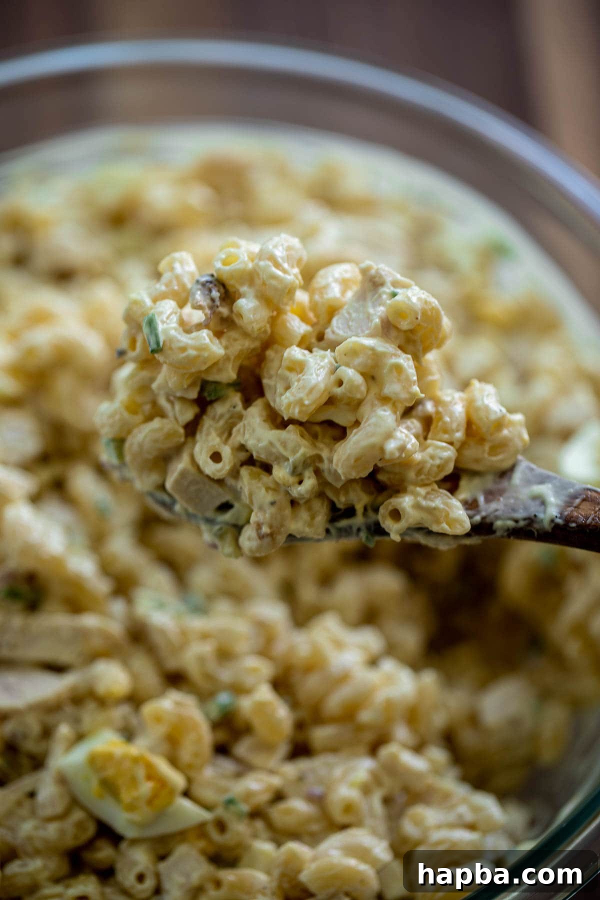Creamy Chicken Macaroni Delight 3 Wooden spoon lifting a portion of creamy macaroni salad, showcasing its rich texture and ingredients.