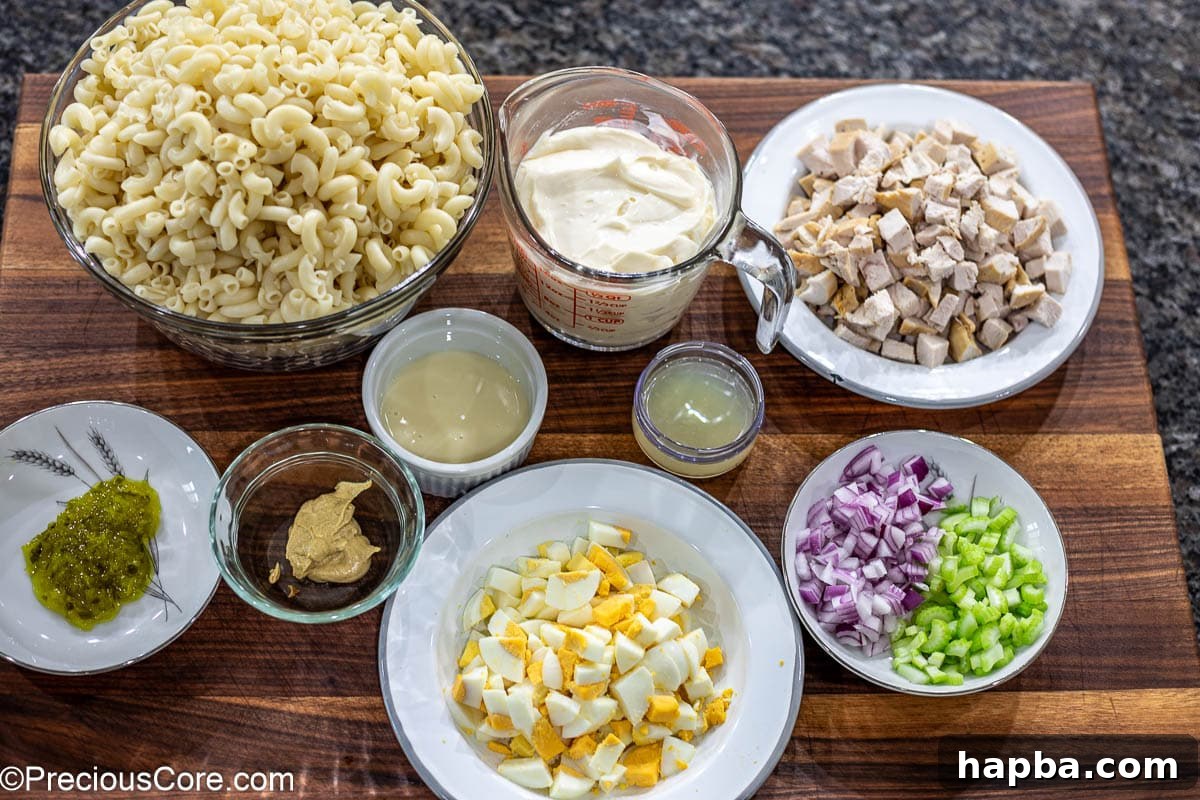 Creamy Chicken Macaroni Delight 4 Fresh ingredients for macaroni salad, including pasta, chicken, eggs, and vegetables, laid out on a chopping board.