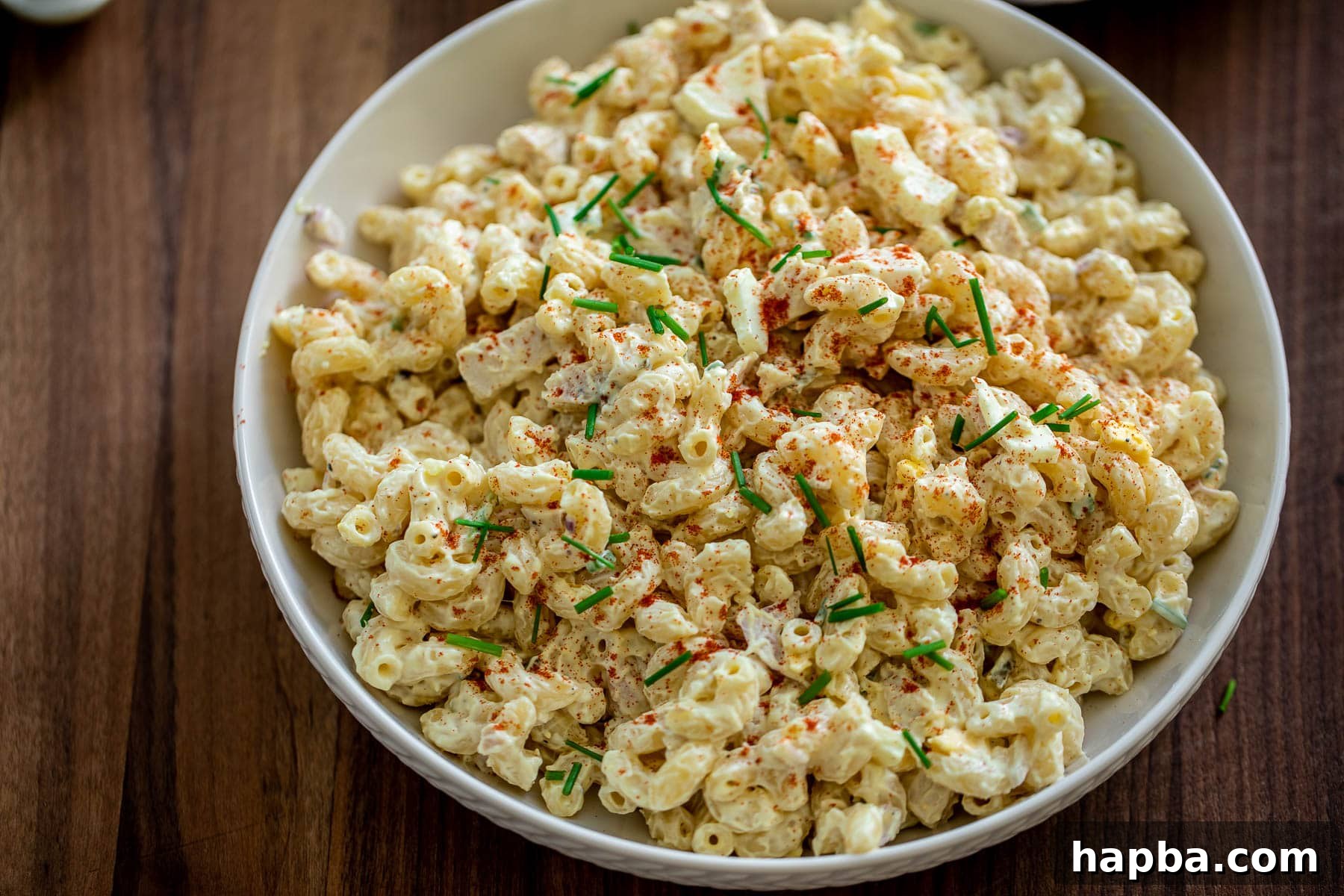 Creamy Chicken Macaroni Delight 10 Landscape view of a large bowl of creamy chicken macaroni salad, garnished with fresh herbs.