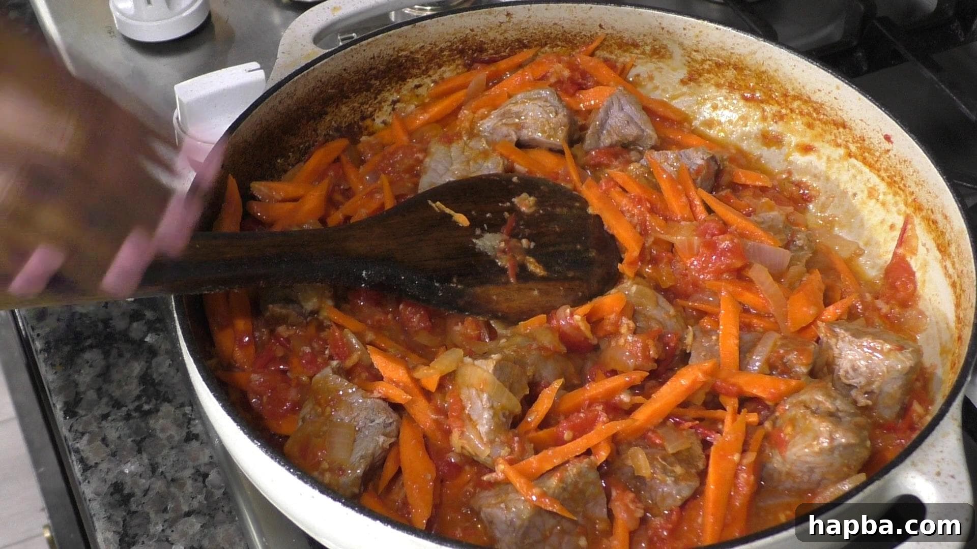 A pot filled with carrots and tender beef simmering in the rich tomato base, building complex flavors.