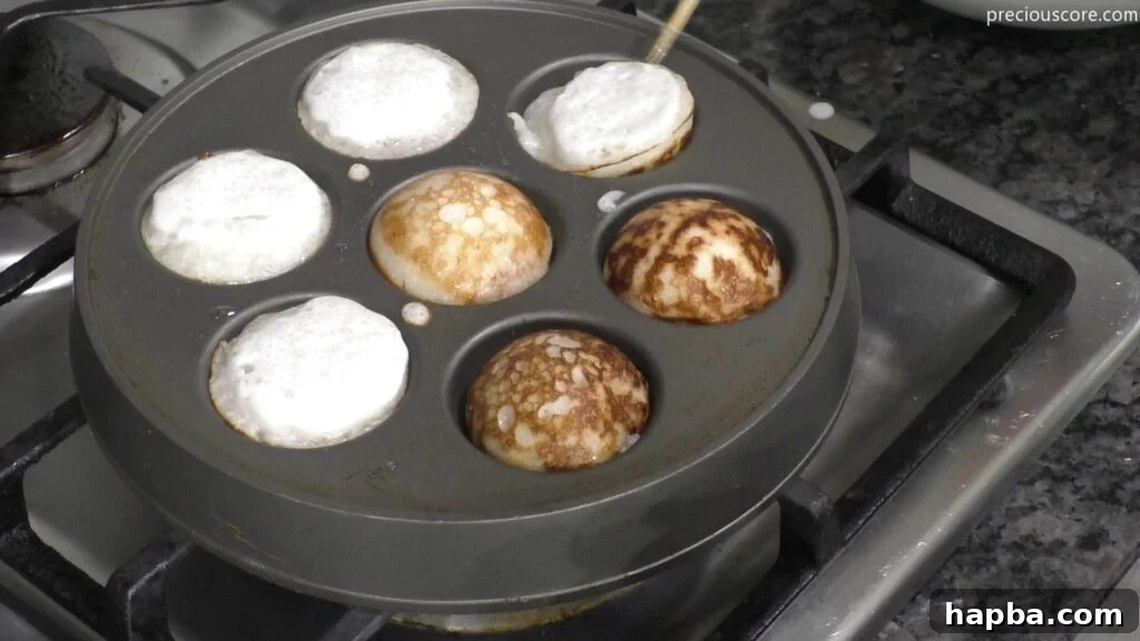 Fluffy East African Coconut Rice Pancakes 7 Cooking Vitumbua coconut rice pancakes on an Aebleskiver pan over medium heat.