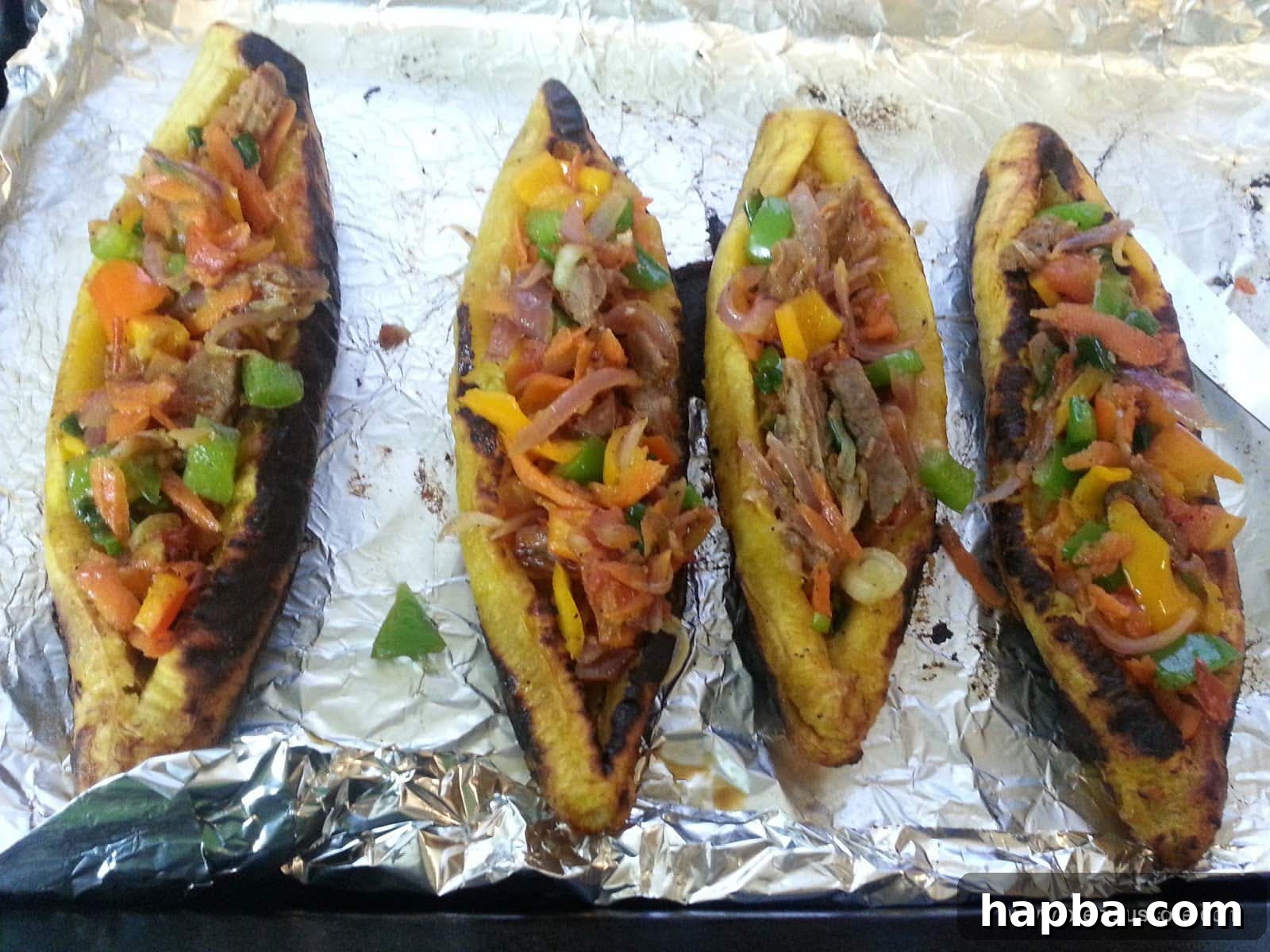 Multiple plantain boats neatly arranged on a baking tray, fully stuffed.