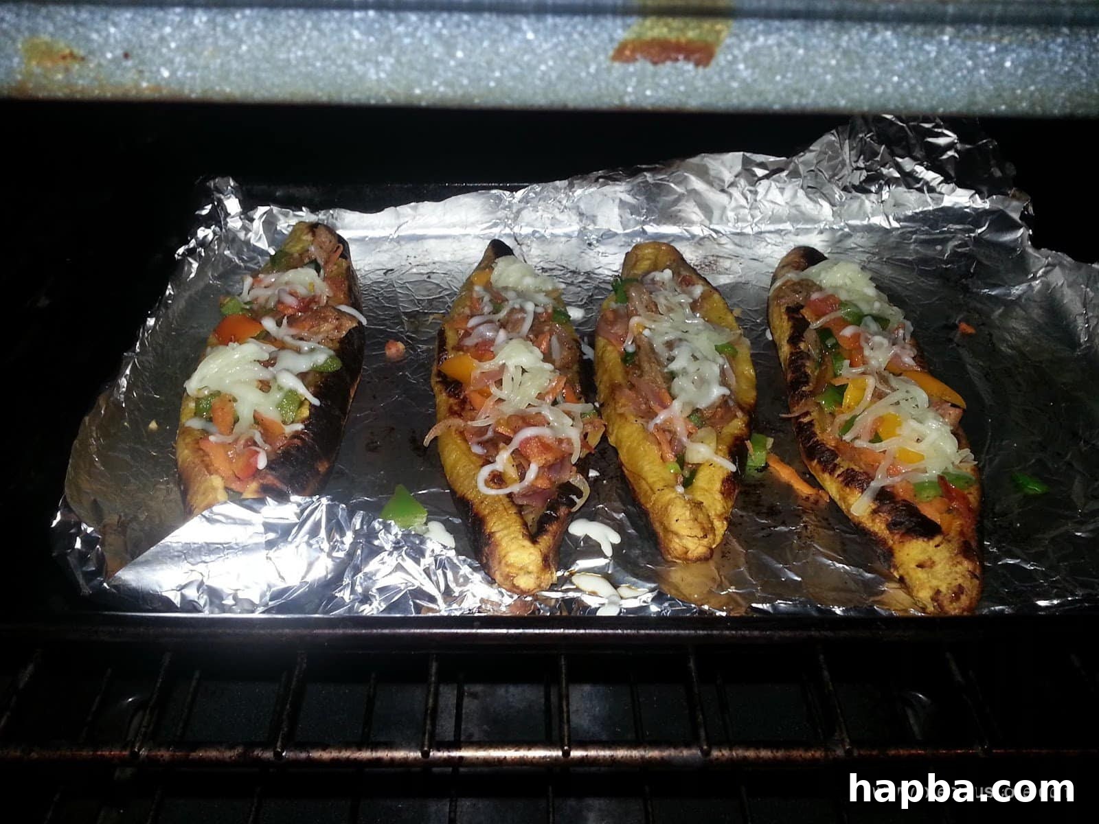 Stuffed plantain boats topped with shredded cheese, ready for the final bake.