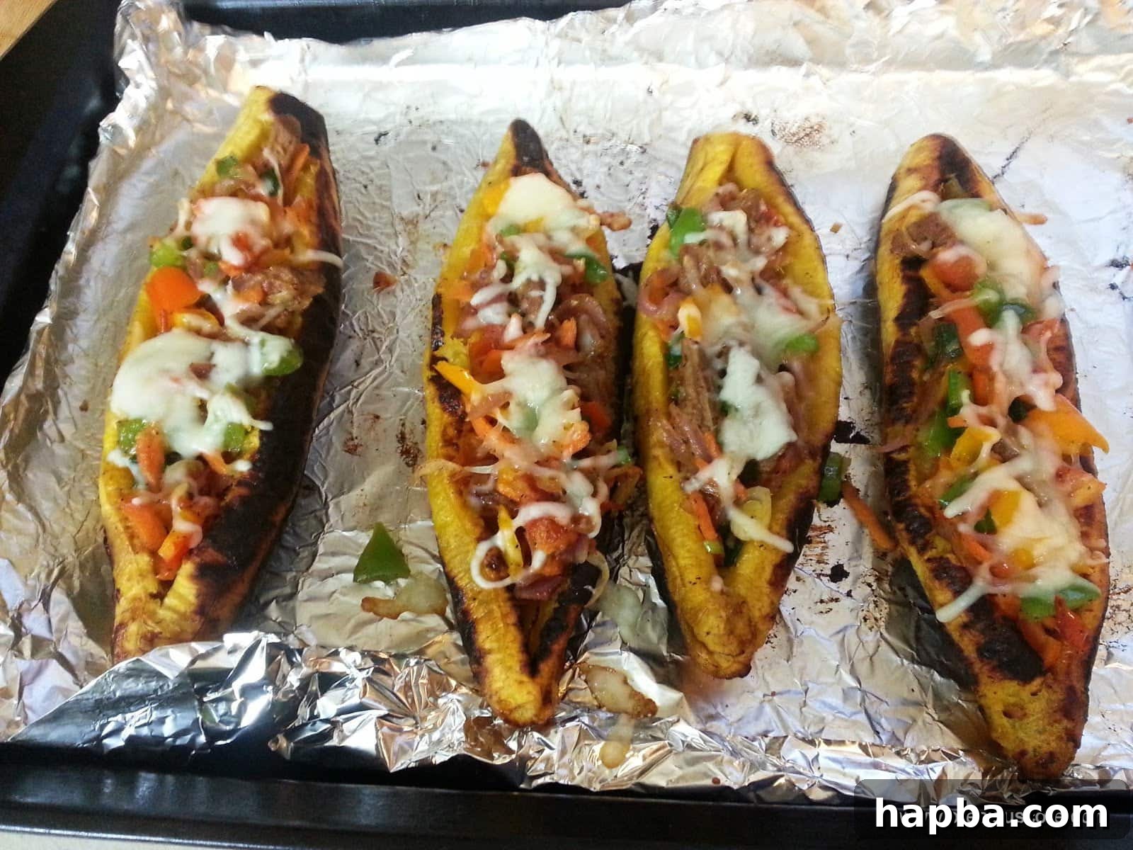 Two plantain boats filled with savory meat and vegetables, ready for baking.