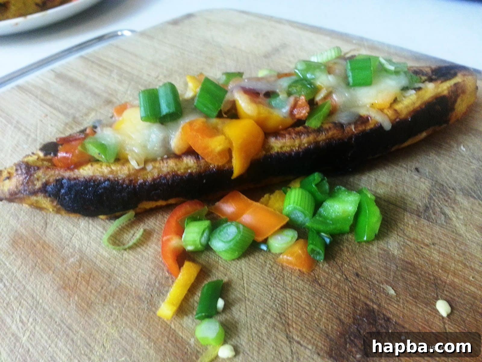 Close-up of a perfectly baked plantain boat, stuffed and topped with melted cheese.