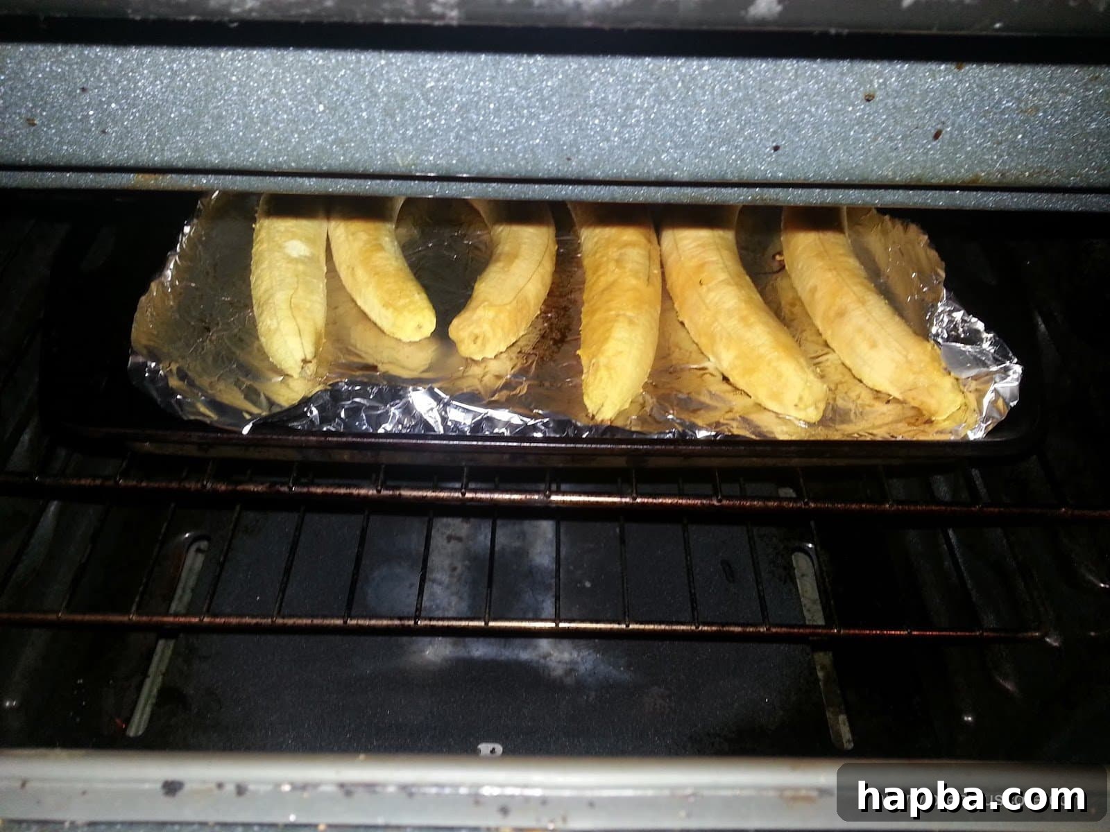 Peeled ripe plantains arranged on a baking tray, ready for roasting.