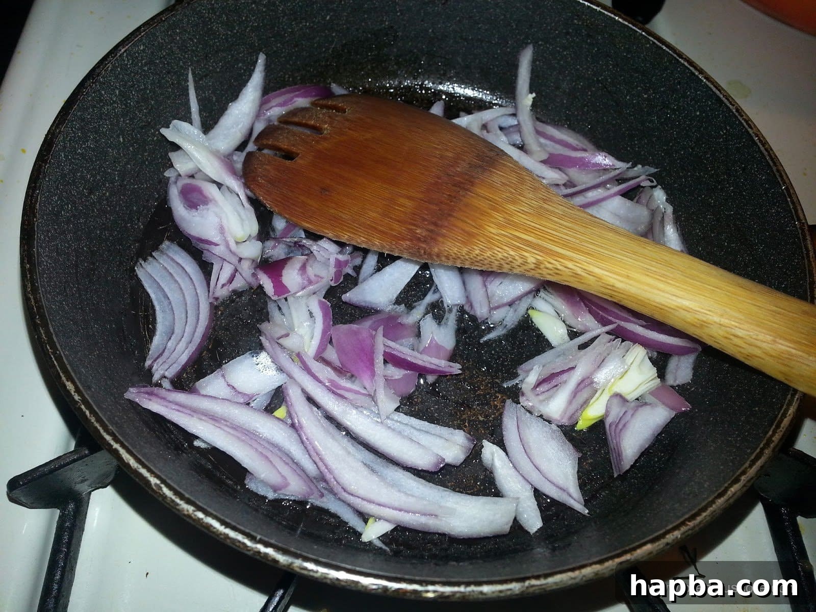 Chopped onions gently sautéing in olive oil in a pan.