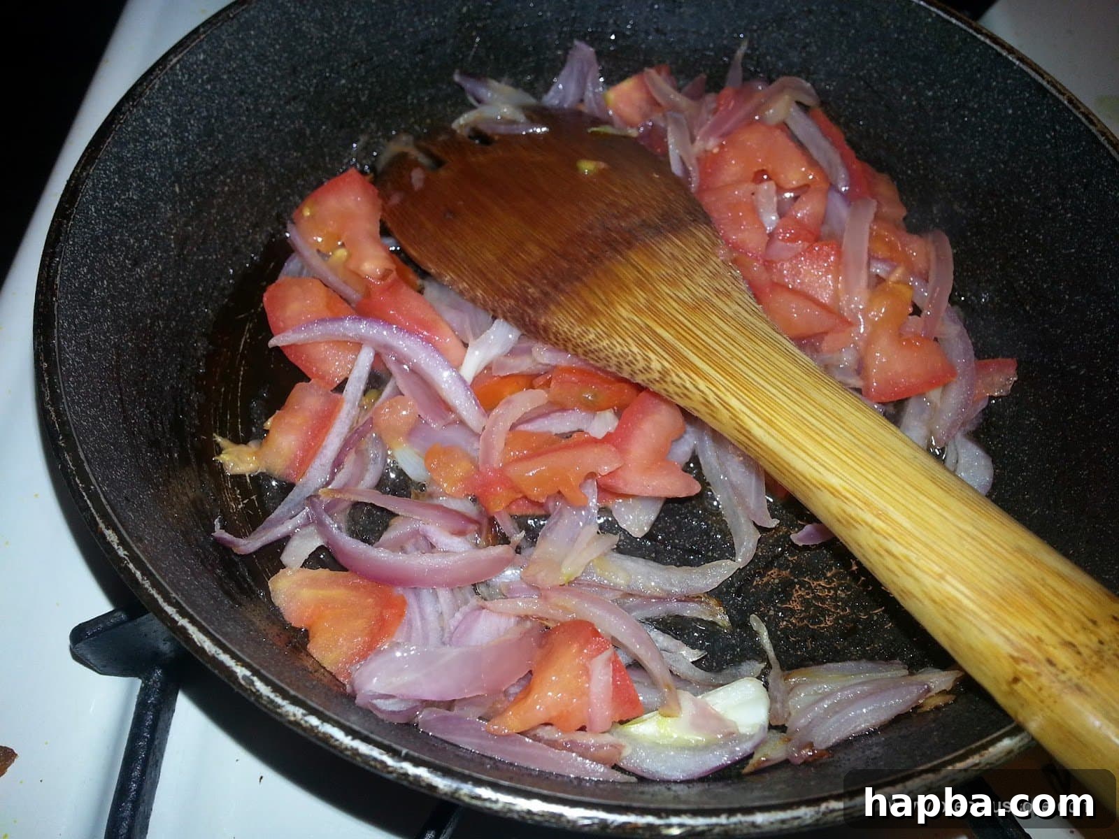 Chopped tomatoes added to the sautéed onions in the pan.
