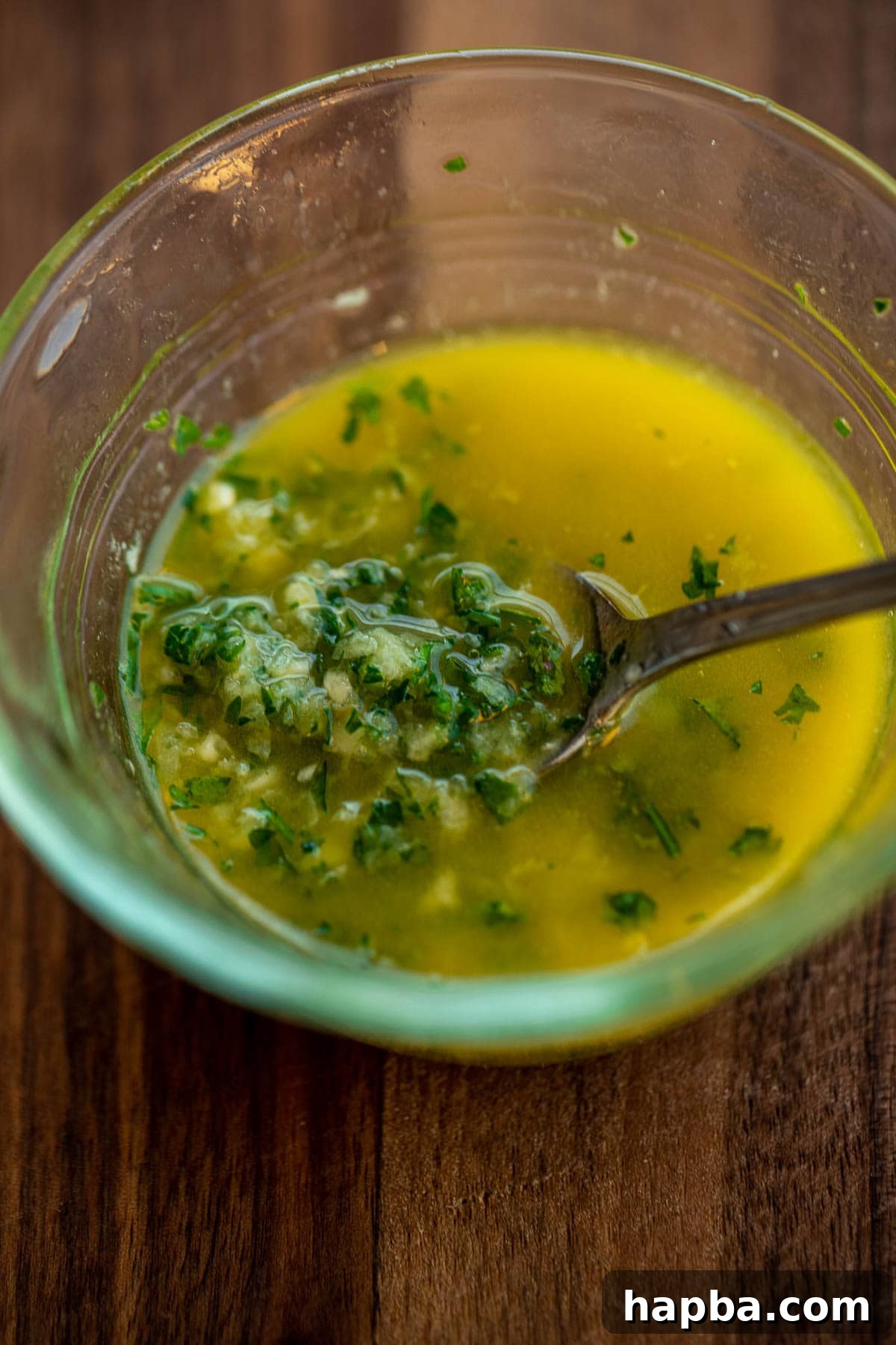 Minced garlic, melted butter, and parsley are combined in a small bowl for the topping.