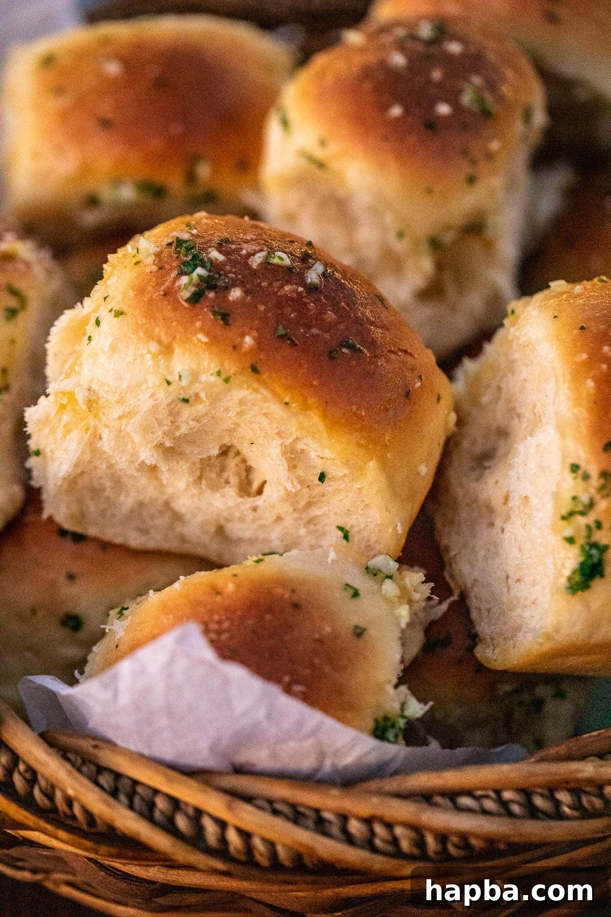 Freshly baked garlic butter rolls piled high in a rustic basket, steam gently rising.