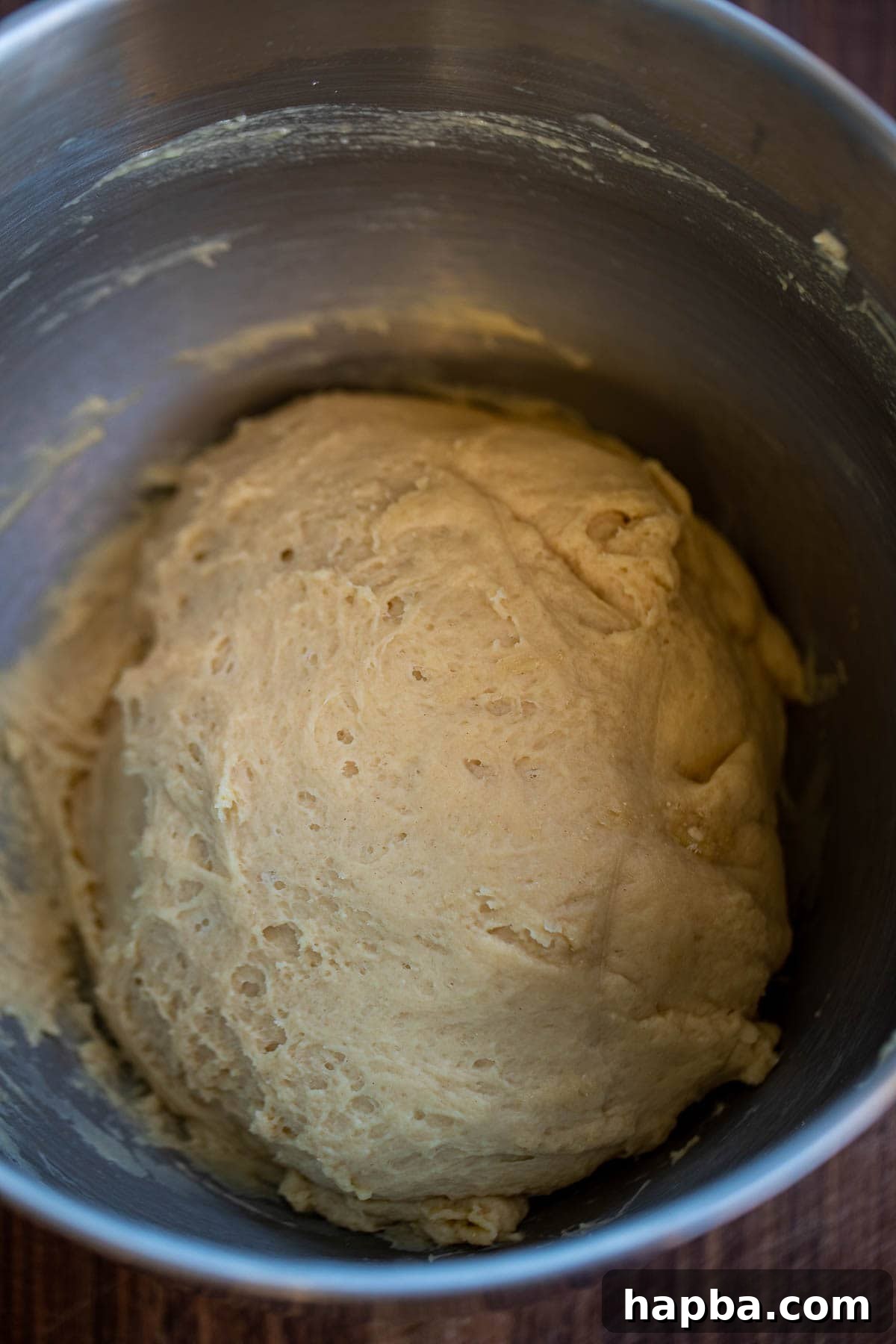 Dough being mixed in a large bowl, showing its initial sticky consistency.