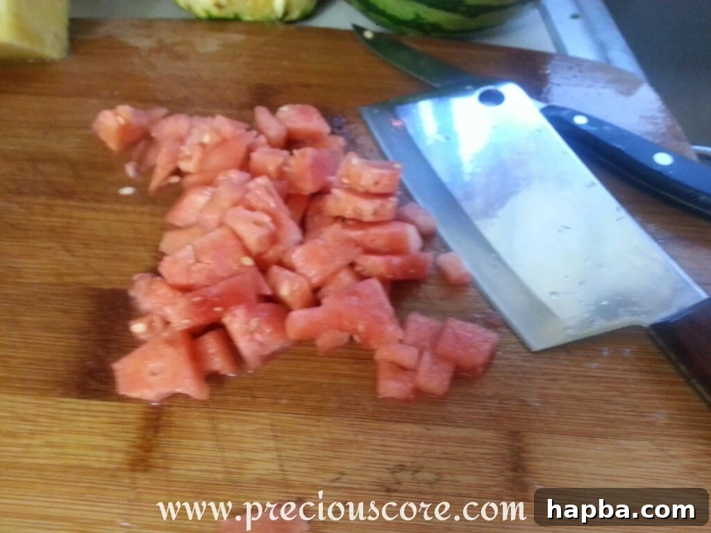 An apple, partially cored and sliced, showing its crisp white flesh, ready for dicing and inclusion in the fruit salad.