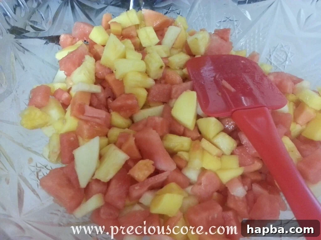 A close-up shot of a beautifully presented bowl of tropical fruit salad, garnished with fresh mint leaves, highlighting the vibrant colors and textures of the fruits, ready to be served.
