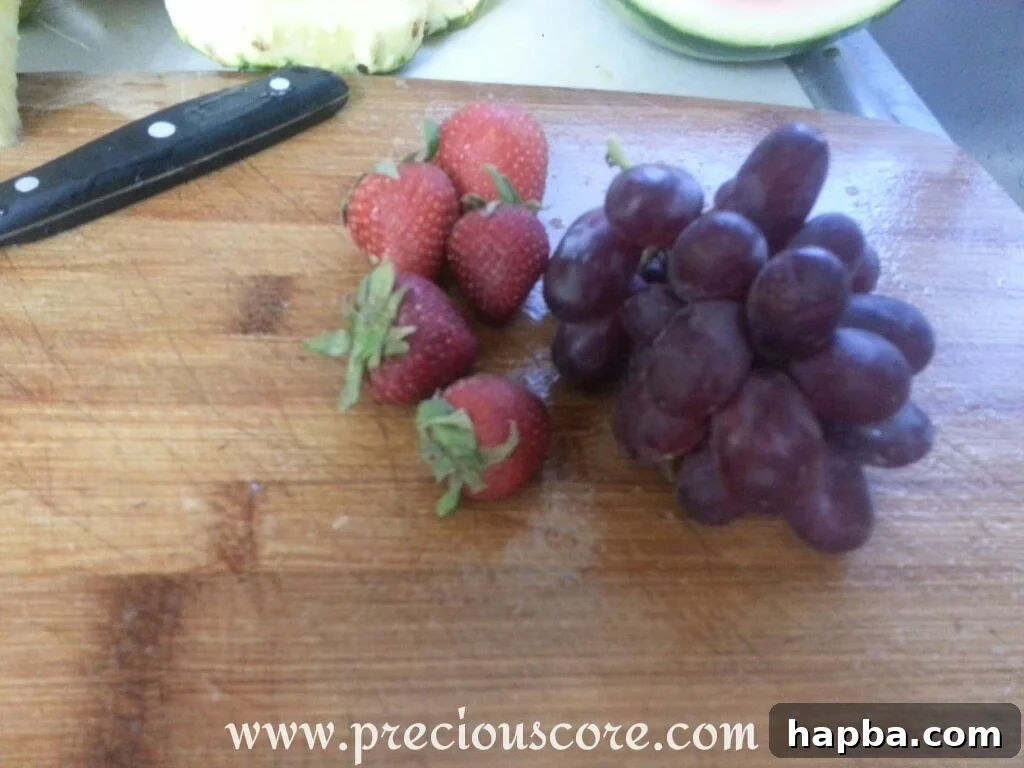 A collection of various colorful fruits that could be added to a fruit salad, including grapes, kiwi, melon, and citrus, offering diverse options.