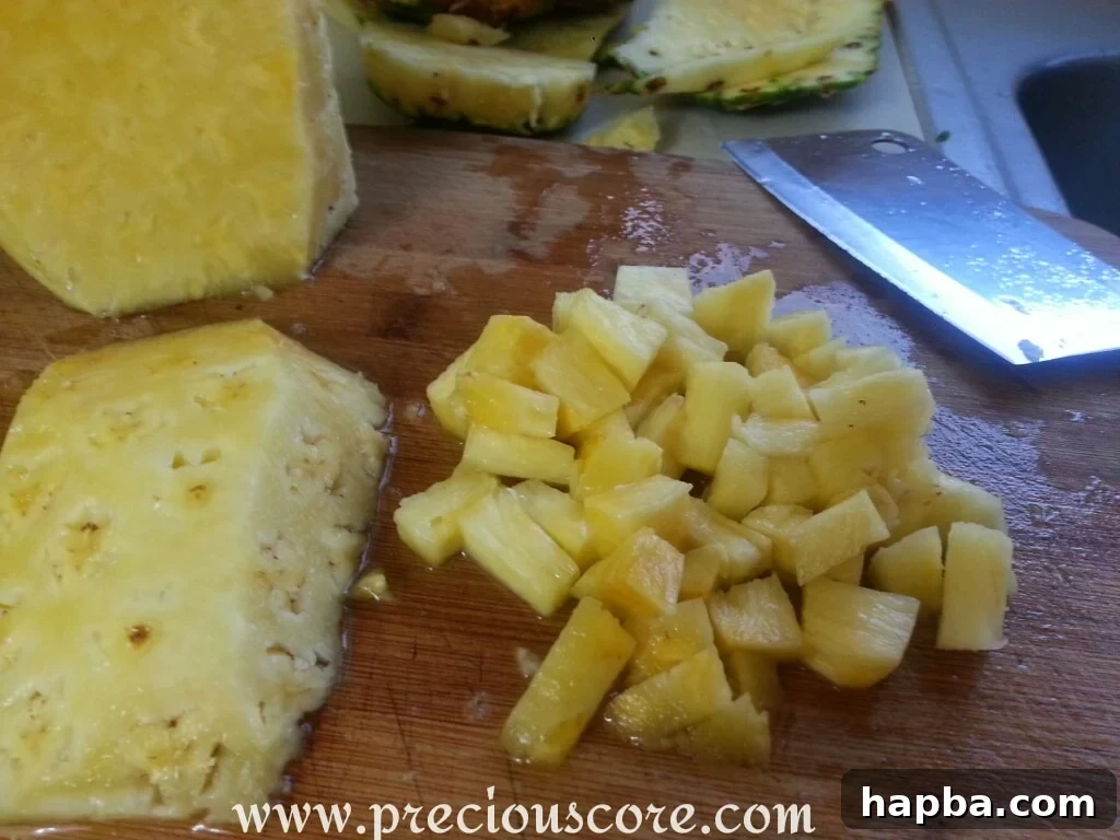 A pineapple being peeled and cored on a cutting board, with the tough central core clearly visible, ready to be removed.