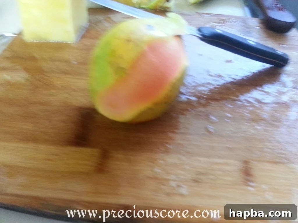 A peeled papaya, cut in half lengthwise, revealing its cavity filled with numerous black seeds, ready for deseeding.