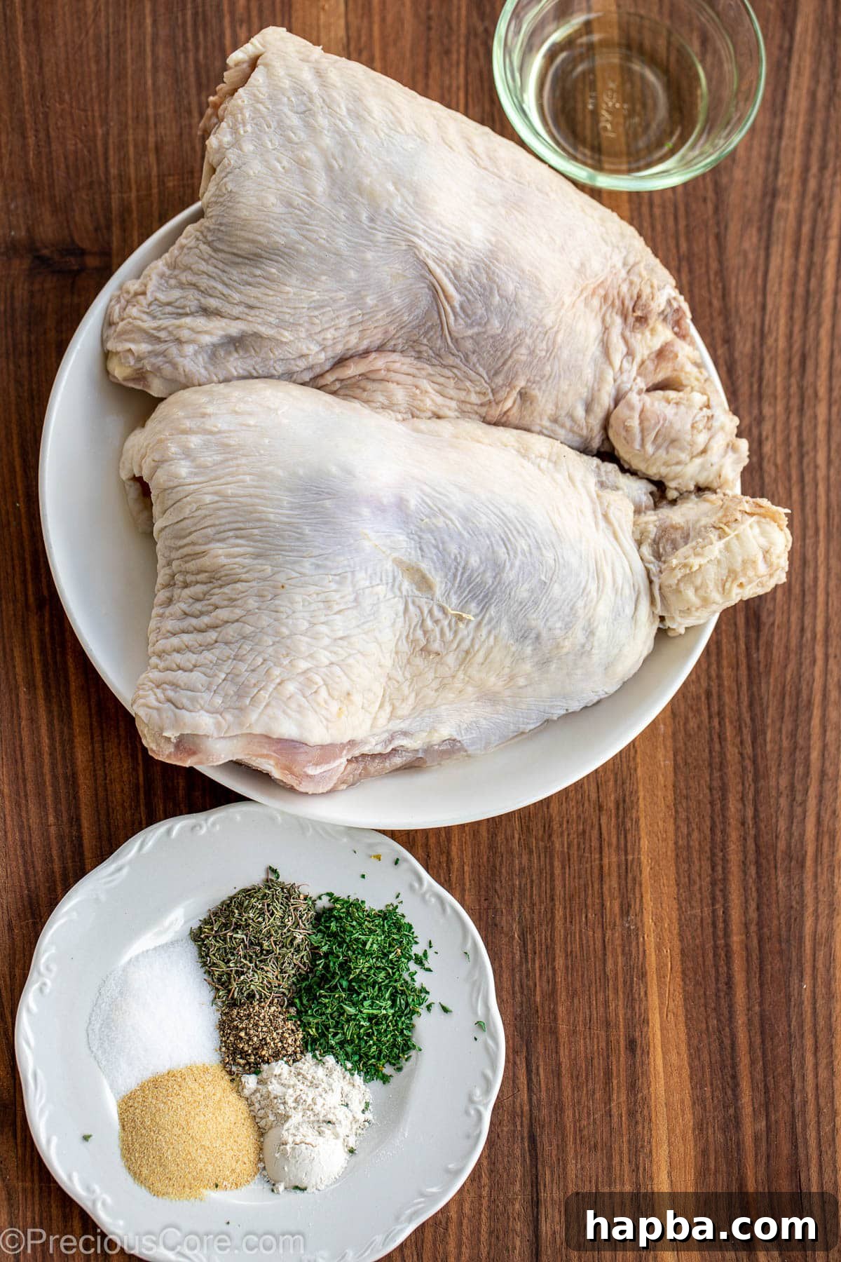 Turkey thighs, a selection of fresh and dried spices, herbs, and seasoning on a rustic chopping board.