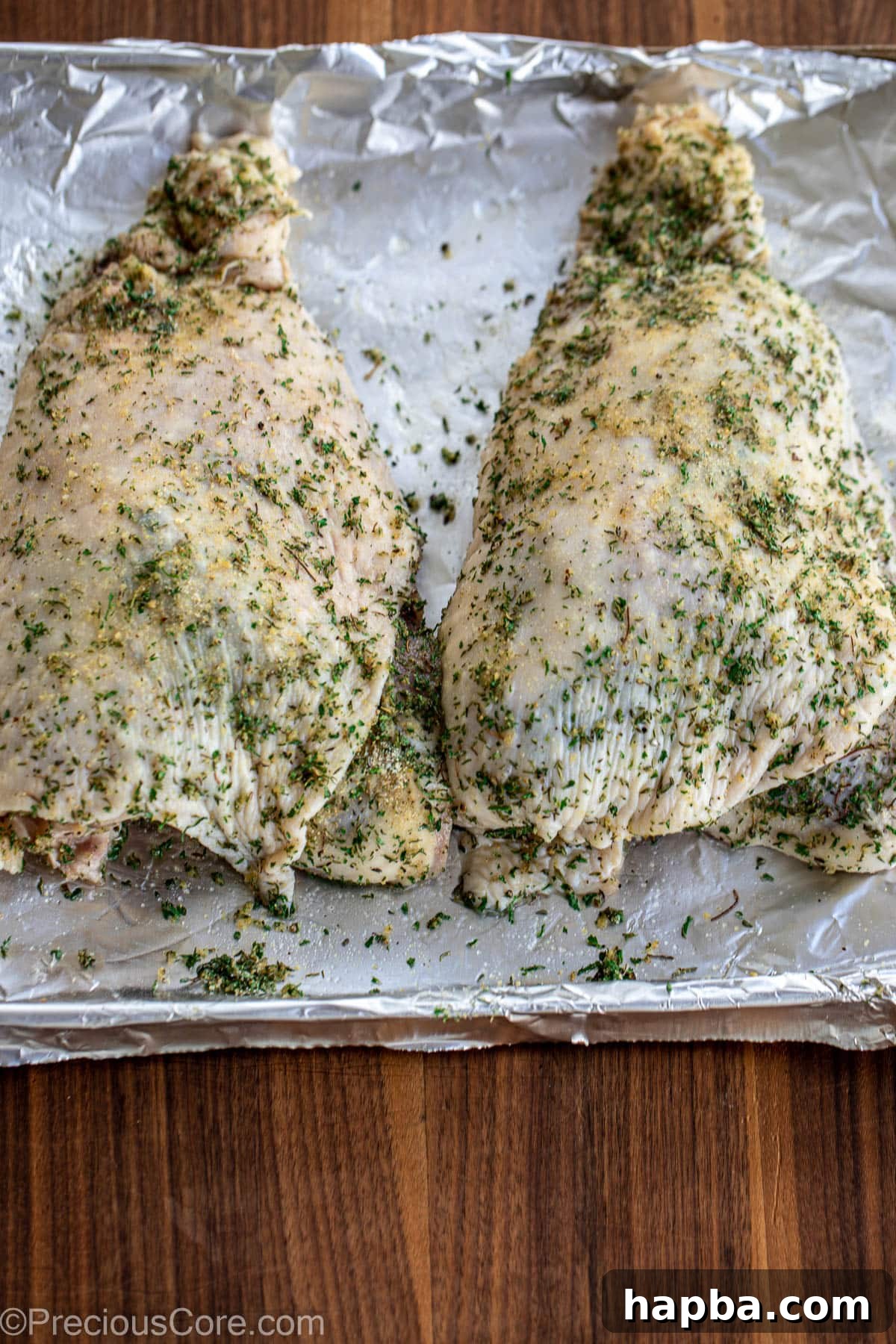 Raw seasoned turkey thighs on a baking sheet, ready for the oven.