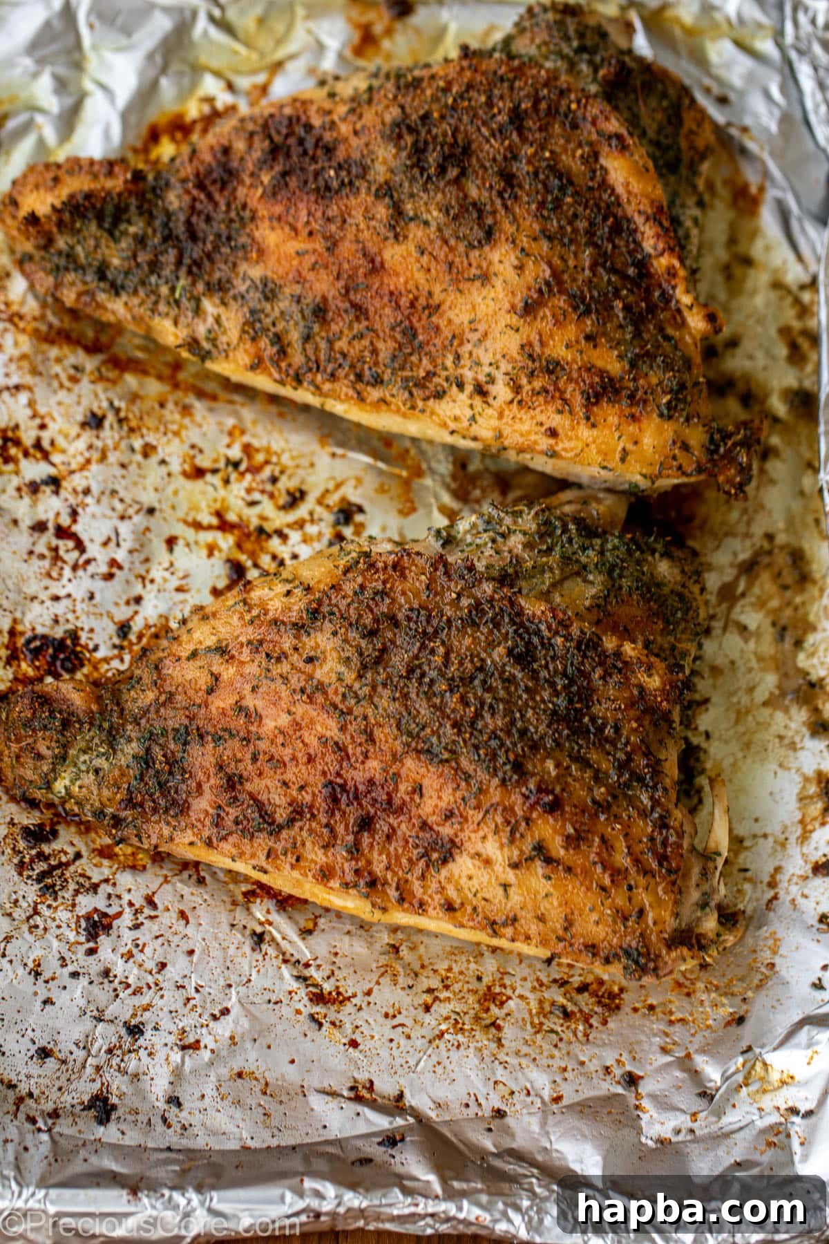 Beautifully roasted turkey thighs resting on a tray lined with aluminum foil.