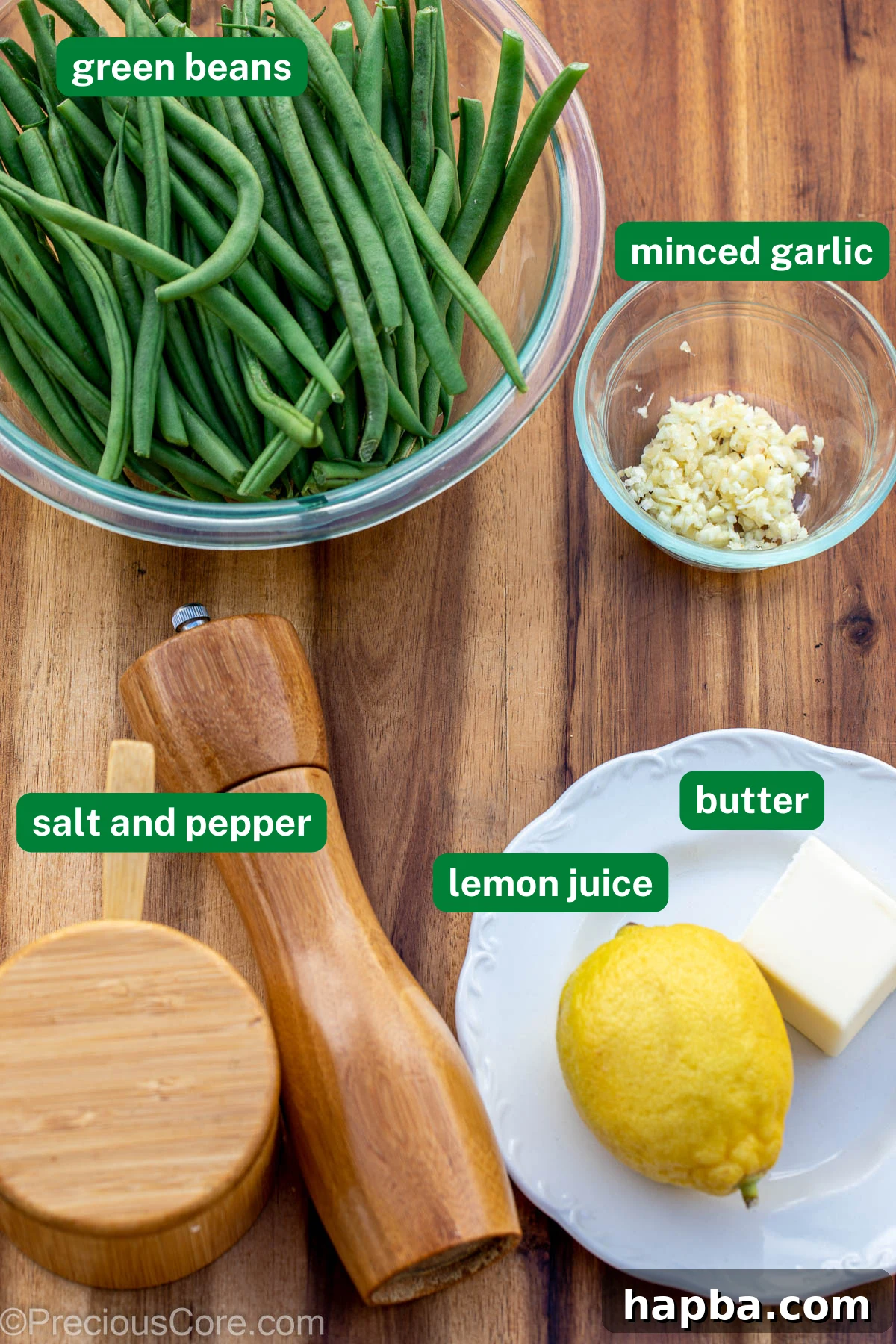 Fresh green beans, minced garlic, salt, pepper, lemon, and butter arranged on a chopping board.