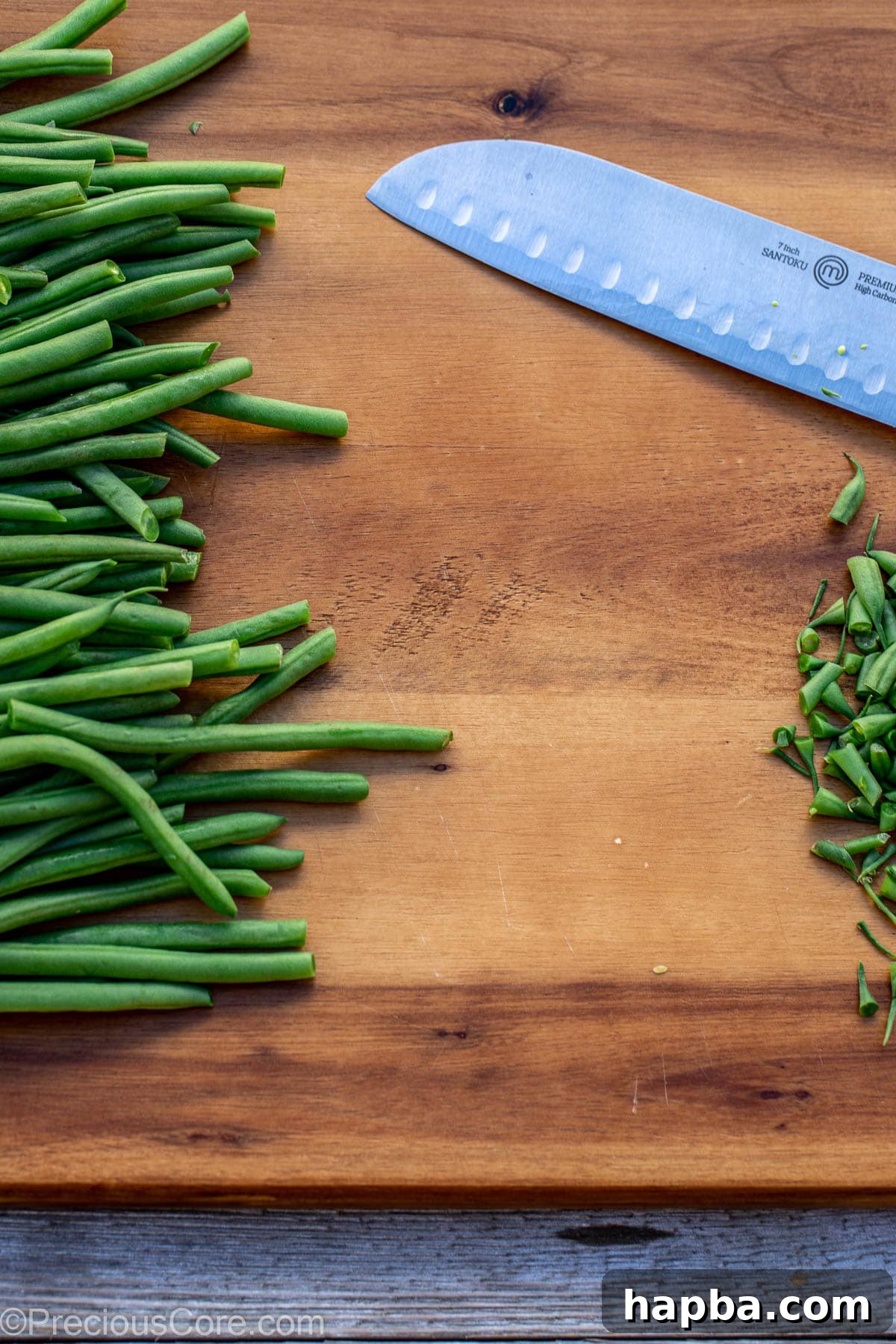 Trimming the stem ends of fresh green beans on a chopping board.