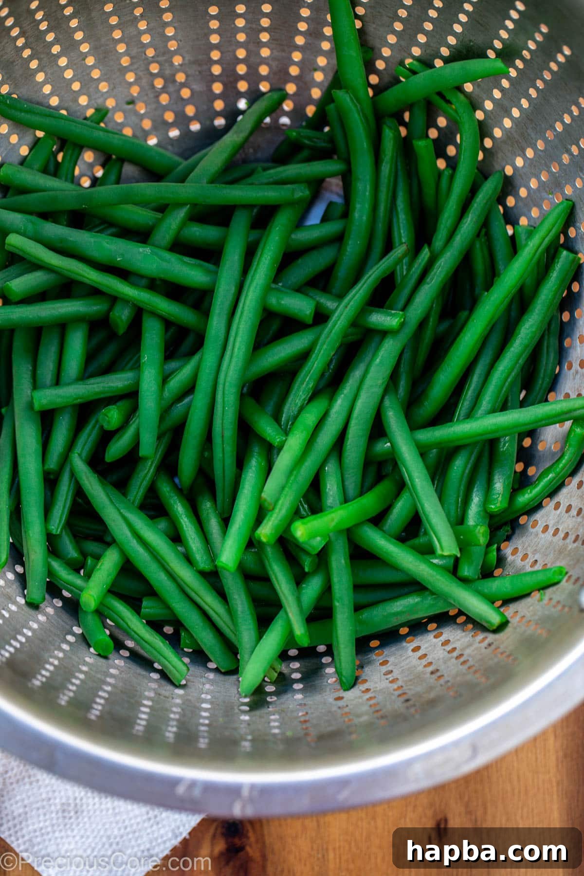 Blanched green beans draining in a colander.