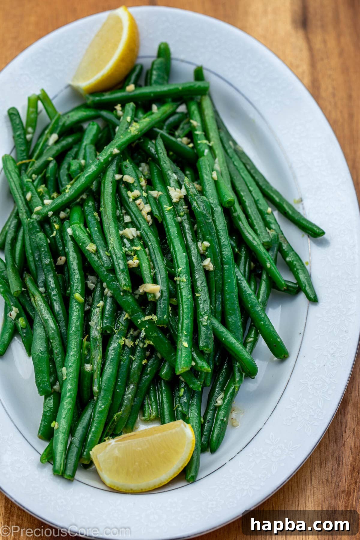 Garlic butter green beans served on a tray with lemon wedges for garnish.