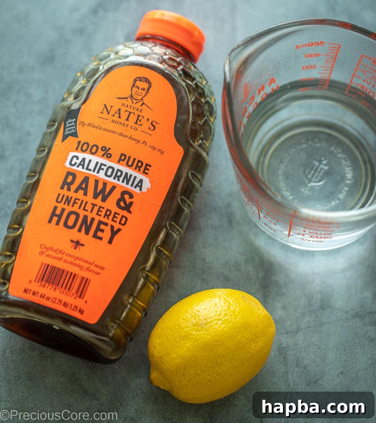 A rustic container of pure honey, a vibrant yellow lemon, and a glass of fresh water, essential for honey lemon tea.