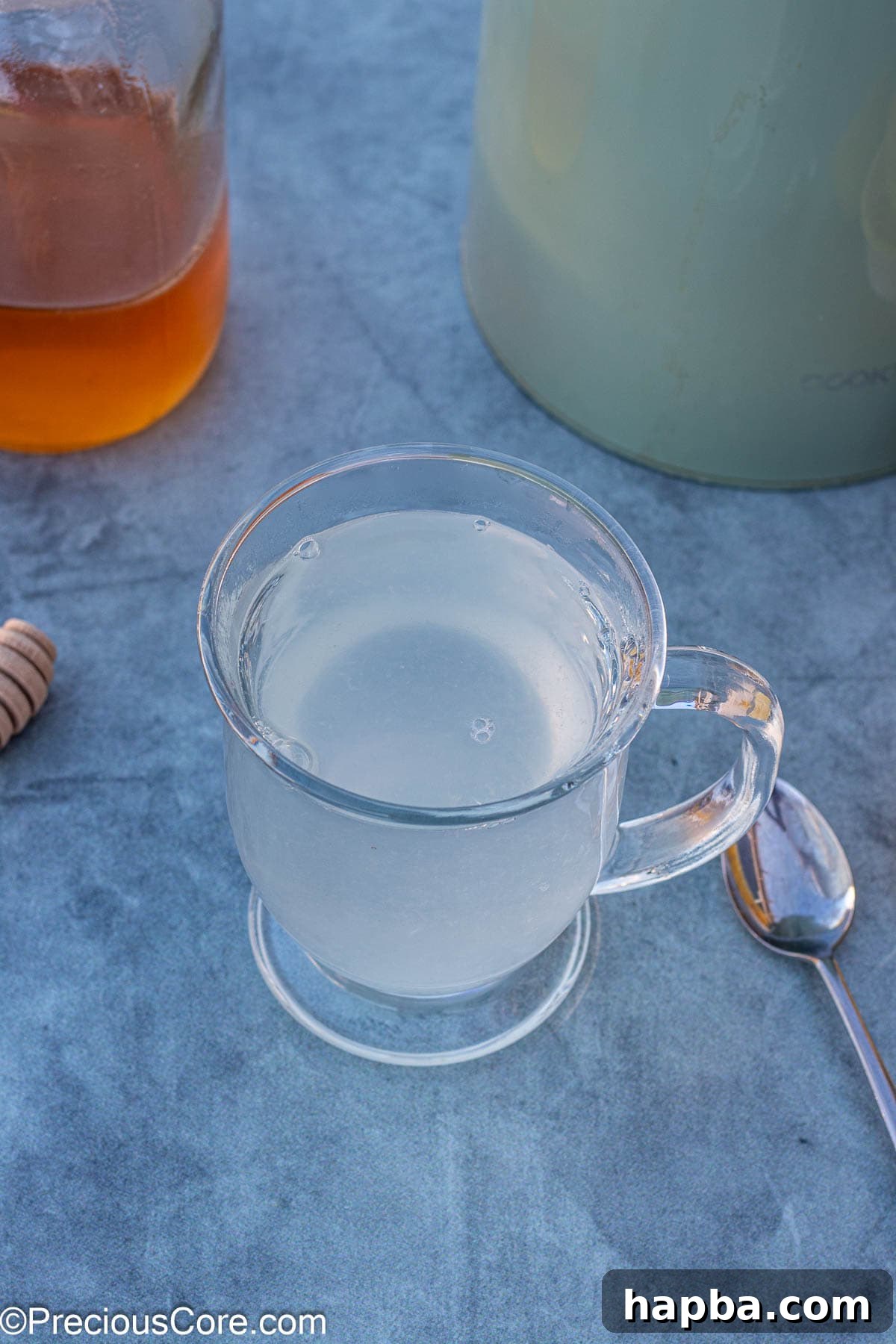 A mug filled with hot water and freshly squeezed lemon juice, awaiting the final ingredient.