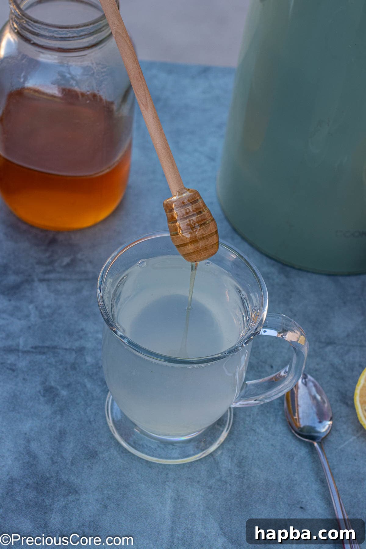 Rich honey being drizzled into a mug of hot lemon tea, creating a perfect balance of sweet and tart.