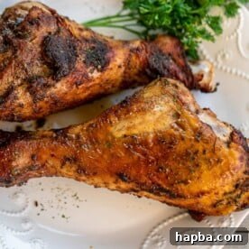 Two perfectly baked, golden-brown turkey drumsticks resting on a plate, ready to be served.