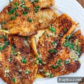 Perfectly cooked lemon butter tilapia fillets beautifully arranged on a white plate, garnished for serving.