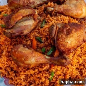 A large serving platter piled high with vibrant Jollof Rice, topped with perfectly cooked chicken thighs and drumsticks, ready for a feast.