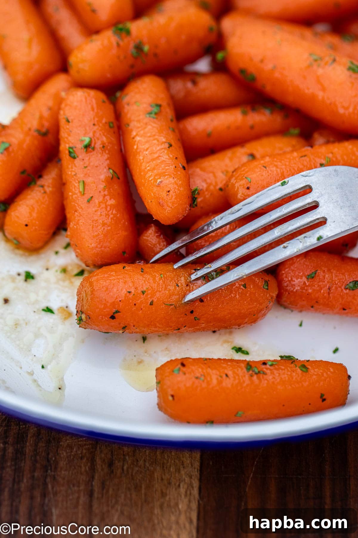 A fork gently piercing into a perfectly cooked, glazed carrot.