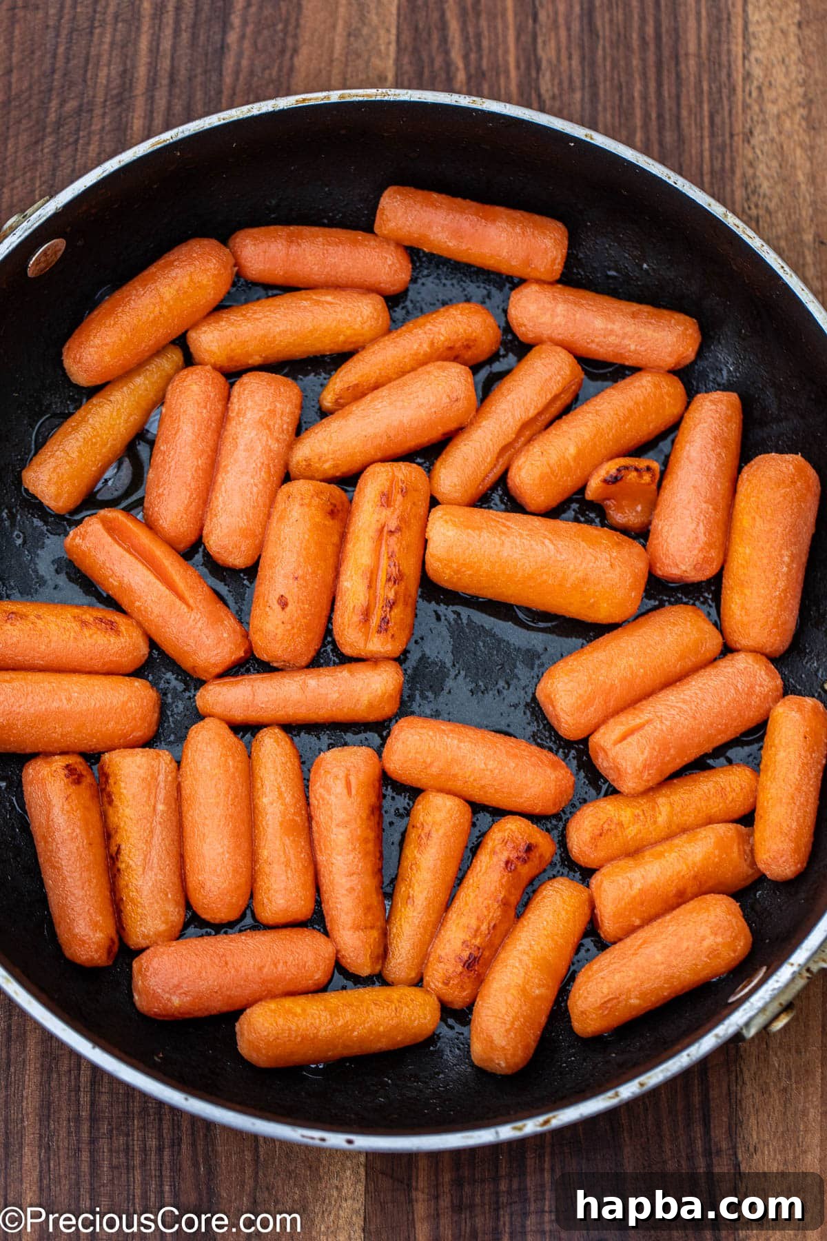 Carrots cooking in melted butter in a skillet on the stovetop.