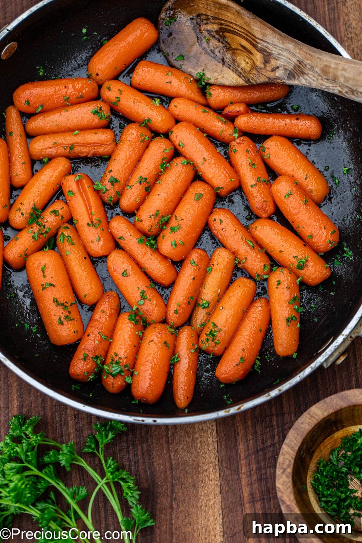 Beautifully glazed carrots garnished with fresh, vibrant parsley on a white plate.