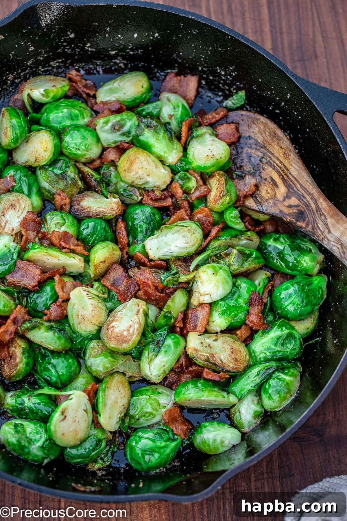Caramelized Brussels Sprouts with Crispy Bacon 2 Pan-fried Brussels sprouts with bacon in a black skillet.