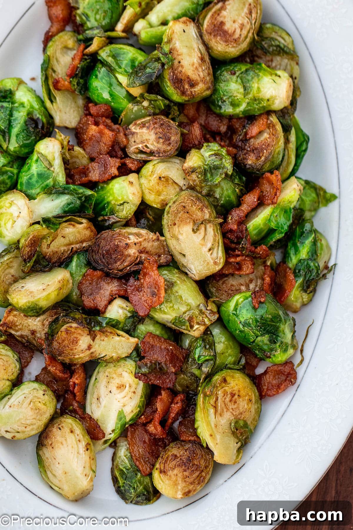 Caramelized Brussels Sprouts with Crispy Bacon 3 Cooked bacon and Brussels sprouts on a white serving plate.