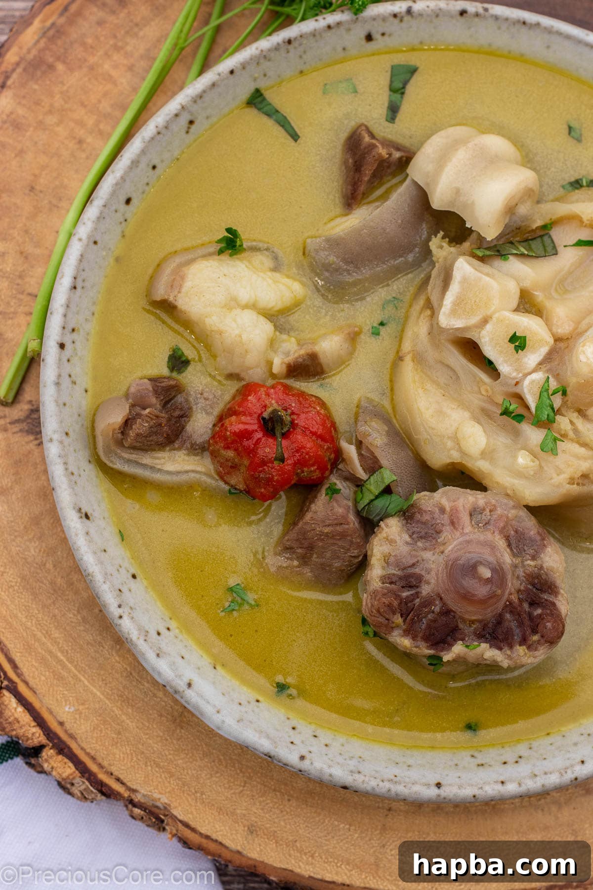 A closer, inviting shot of the flavorful pepper soup, showing tender pieces of meat and a rich, clear broth in a ceramic bowl.