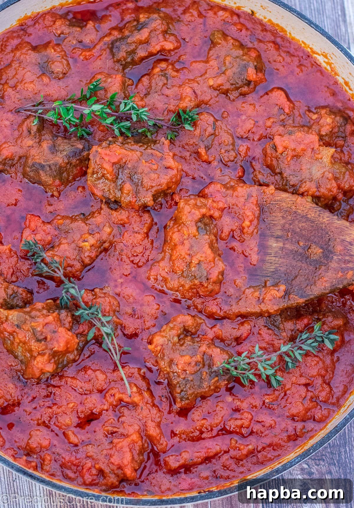 A large pot filled with rich, red Nigerian tomato beef stew, ready to be served.