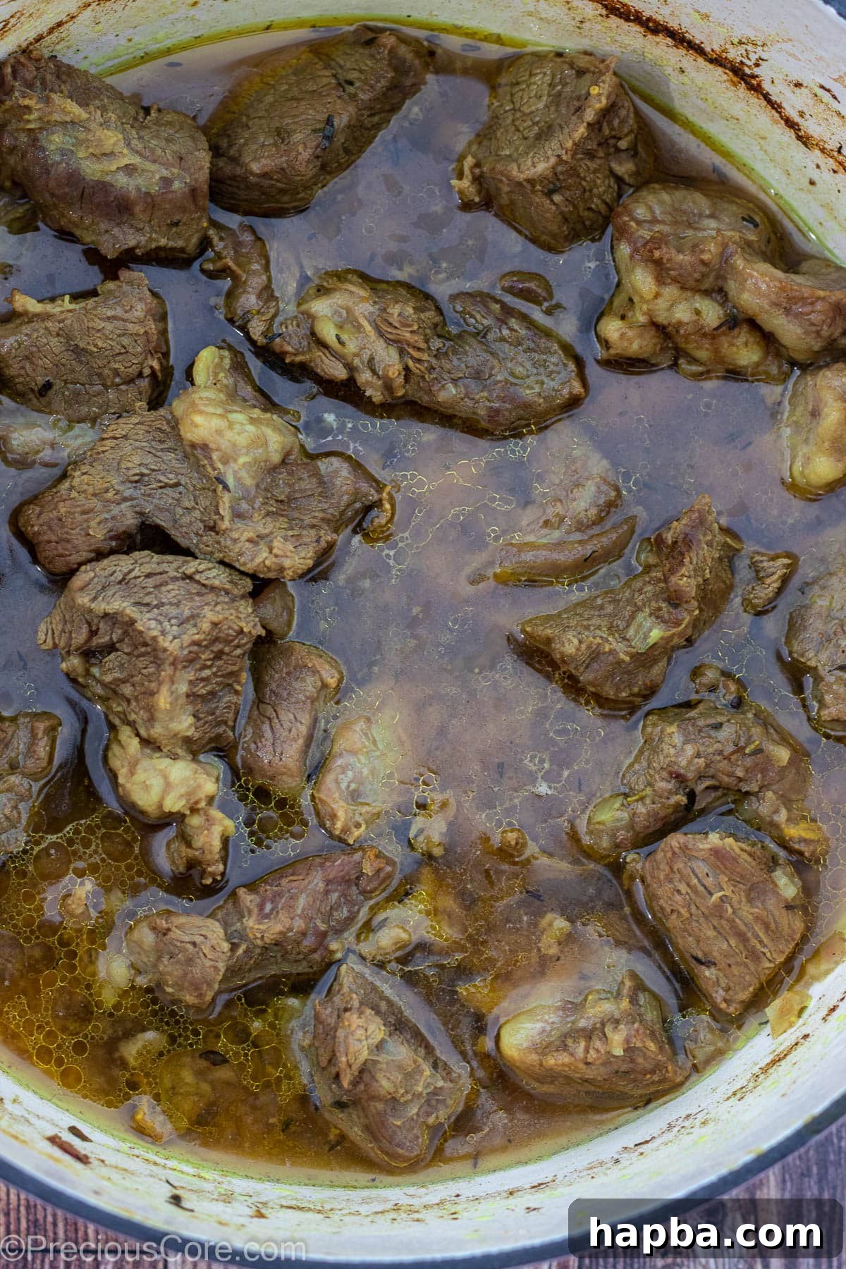 Tender, cooked beef resting in its flavorful stock in a pot.
