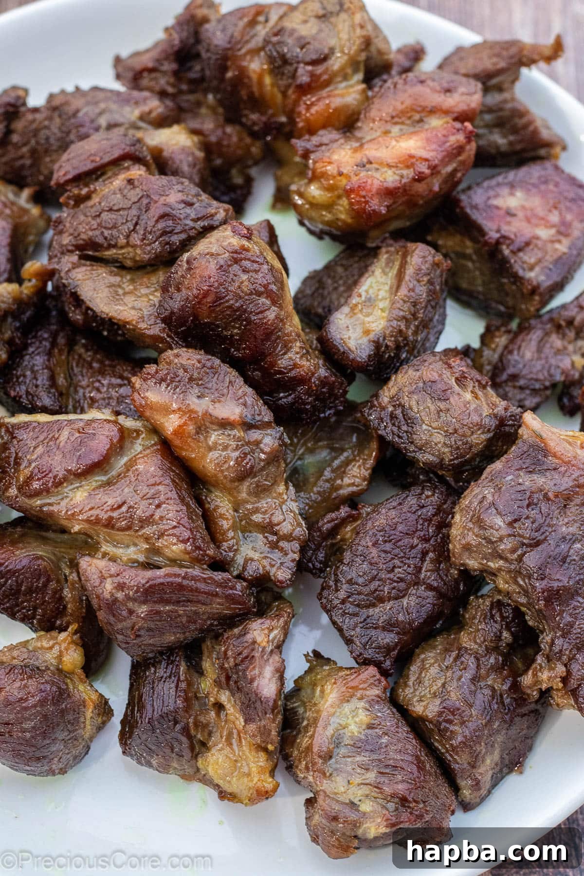 Golden-brown fried beef pieces arranged on a white plate after being seared.