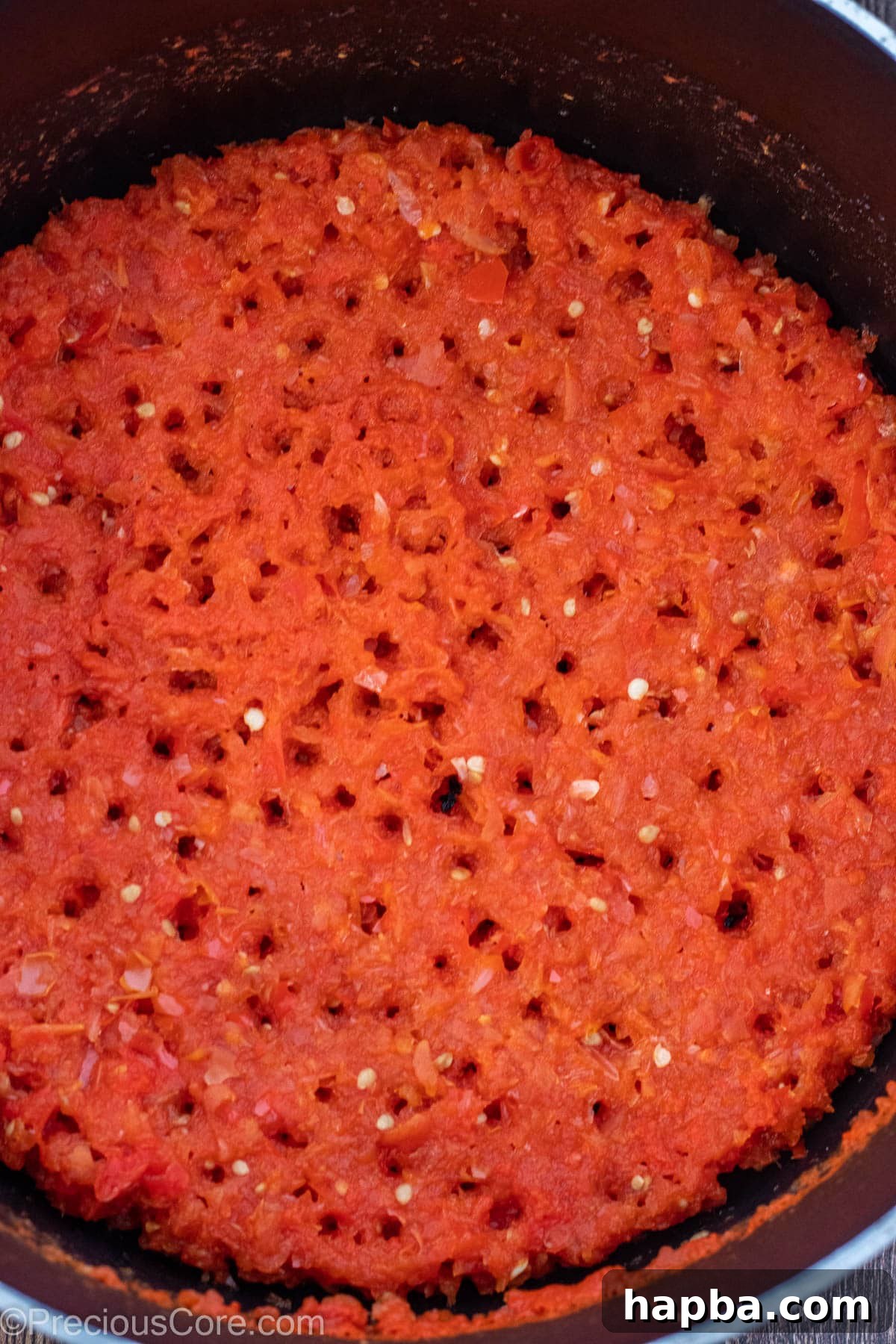 A pot of the blended tomato, bell pepper, and onion mixture simmering until reduced and thickened.