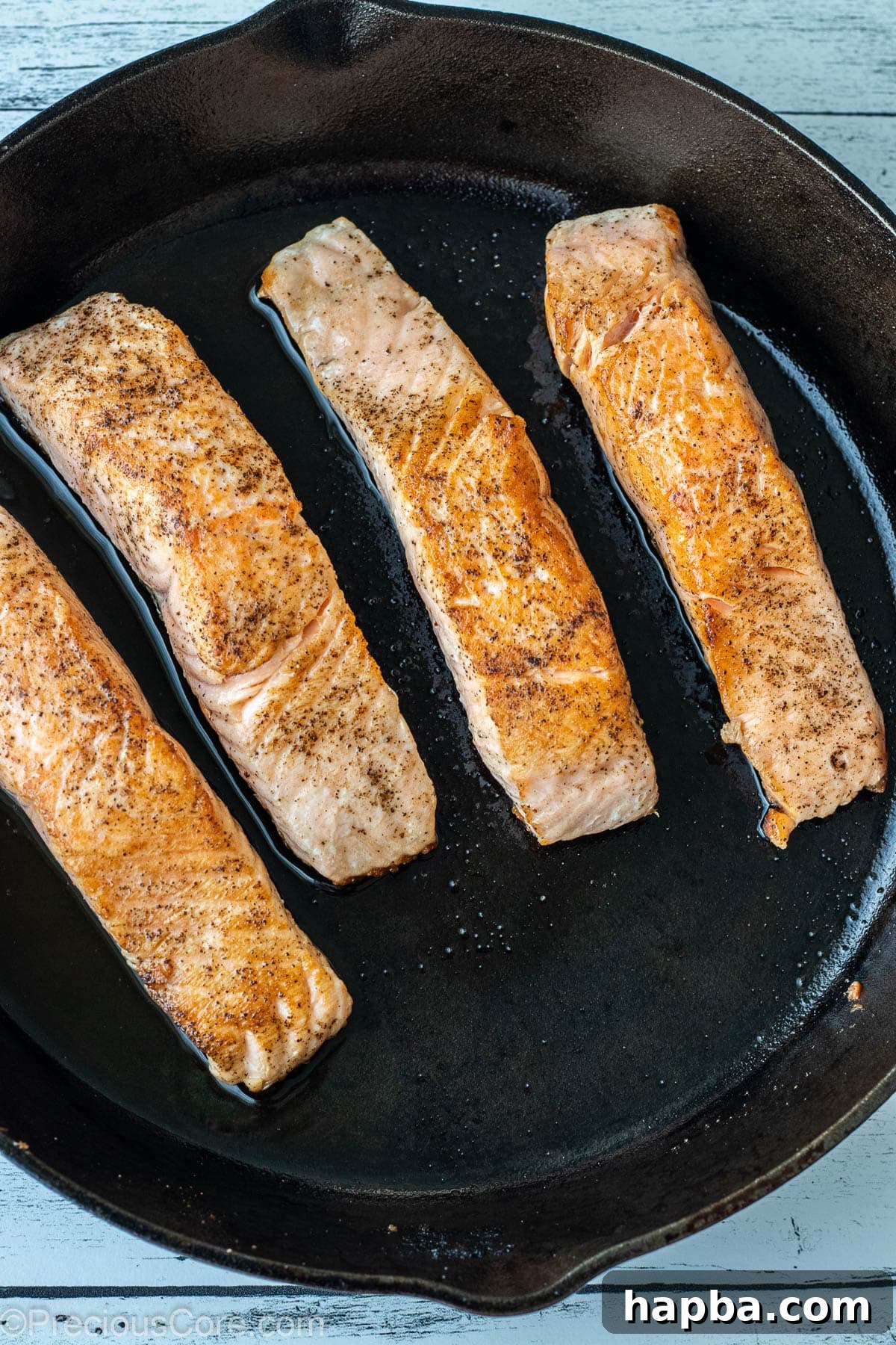 Zesty Lemon Butter Salmon 5 Seared salmon fillets in a cast iron skillet.