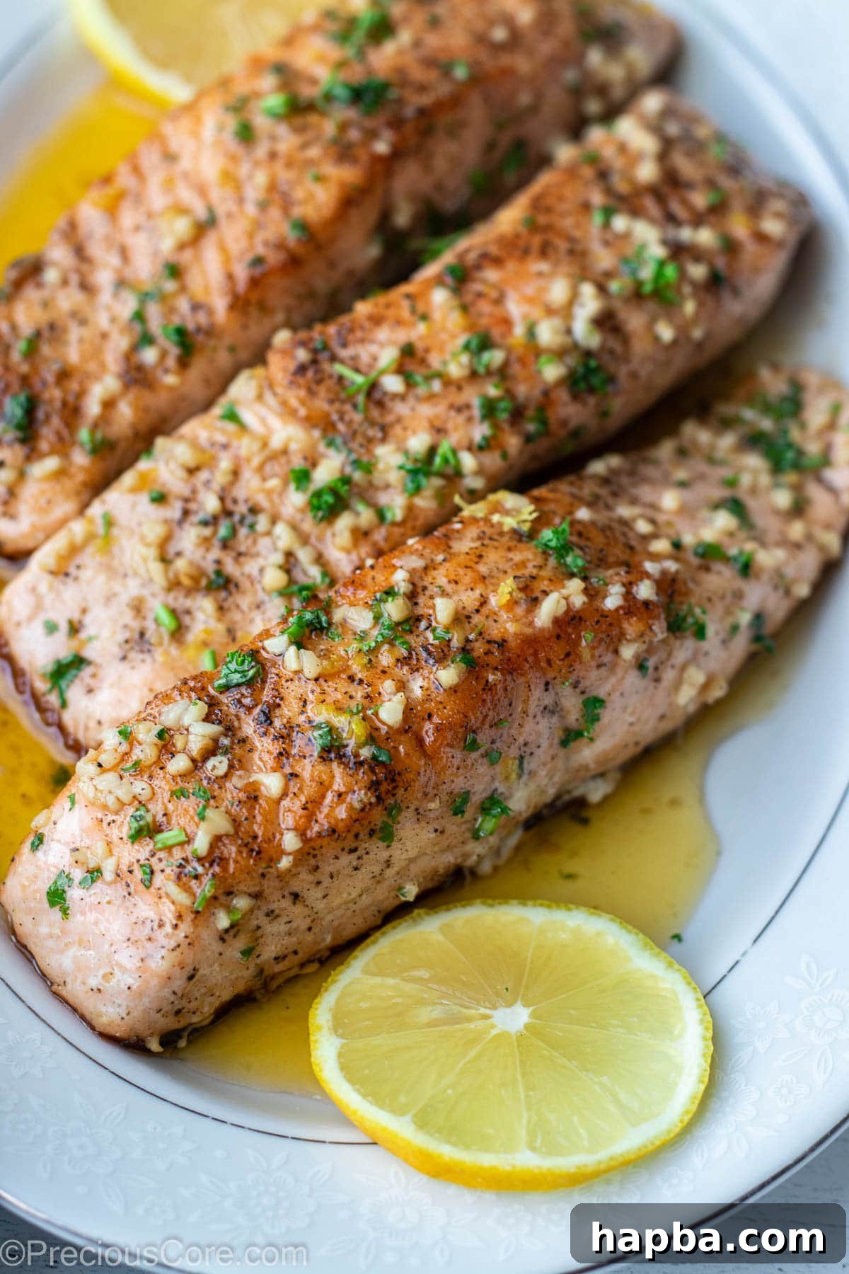 Zesty Lemon Butter Salmon 10 Cooked salmon fillets on a serving tray over lemon butter sauce.